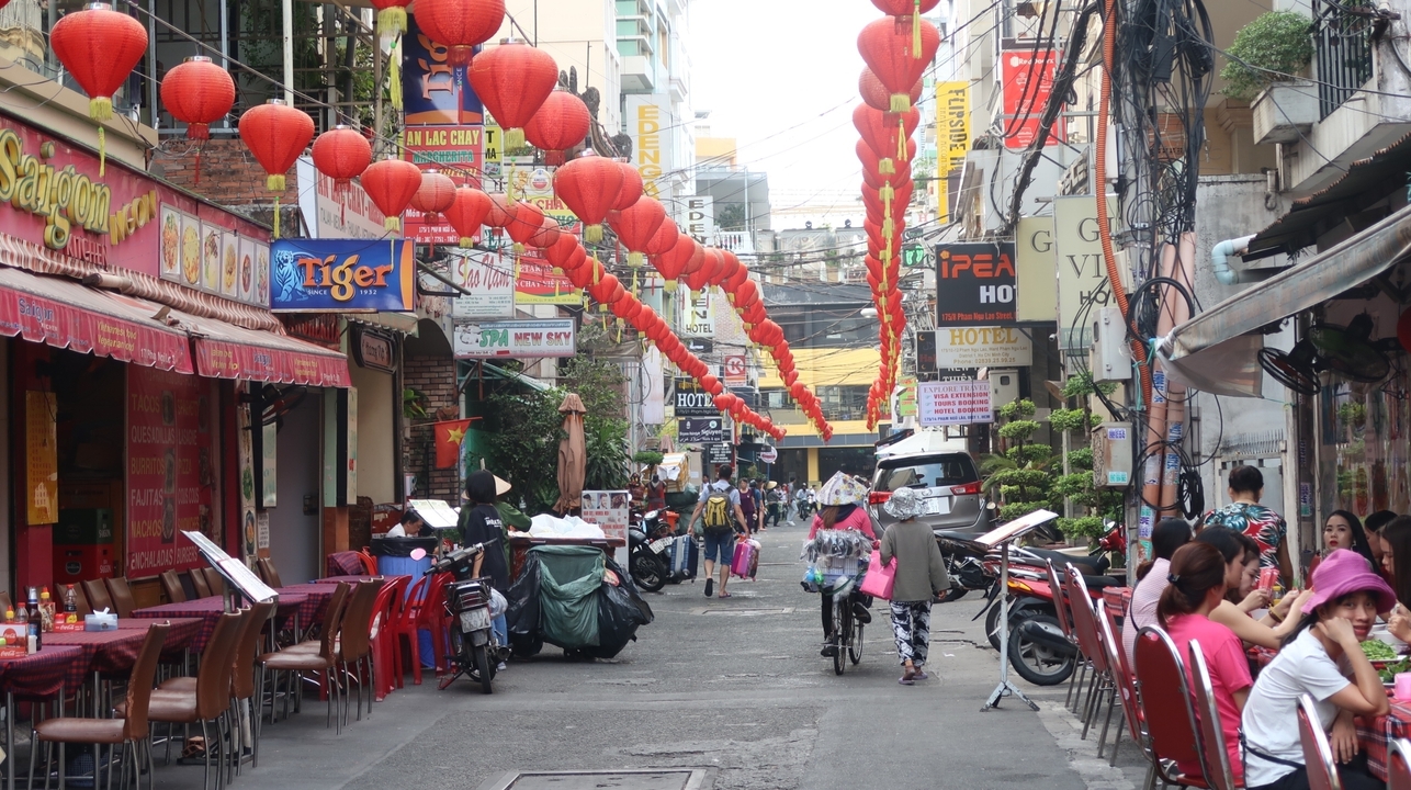Busy street in Vietnam adorned with red lanterns and bustling with people.