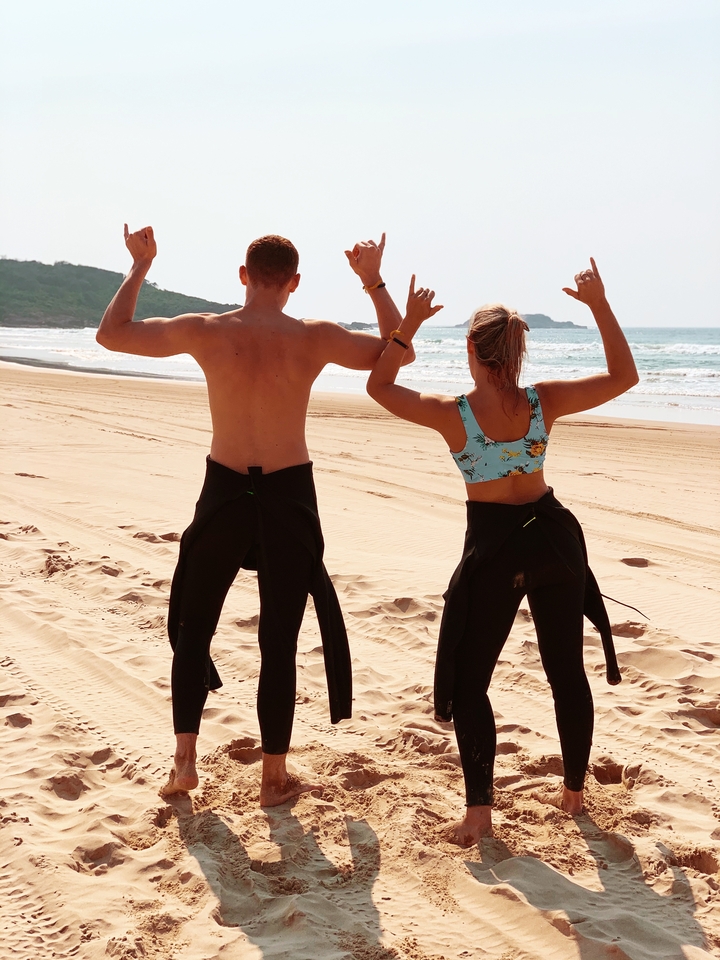 Deux personnes en combinaisons de plongée posant sur la plage.