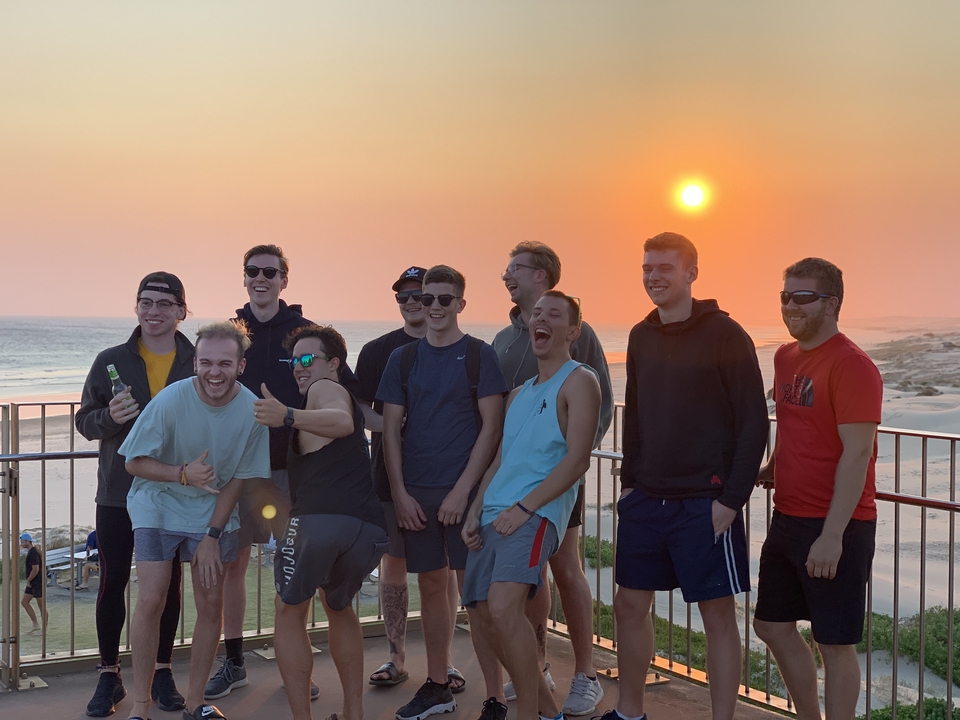 Groupe d'amis riant et profitant de la vue sur la plage au coucher du soleil.
