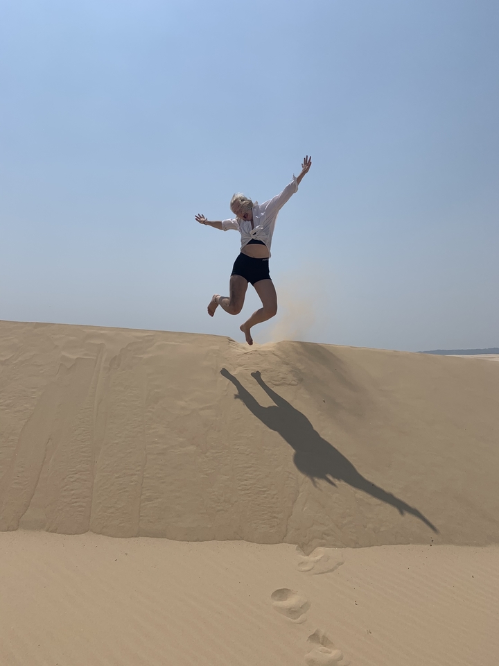 Personne sautant sur des dunes de sable.