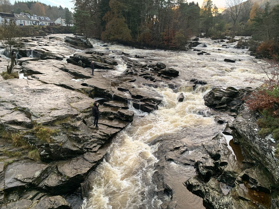 Personne debout sur des rochers près d'une cascade de rivière.