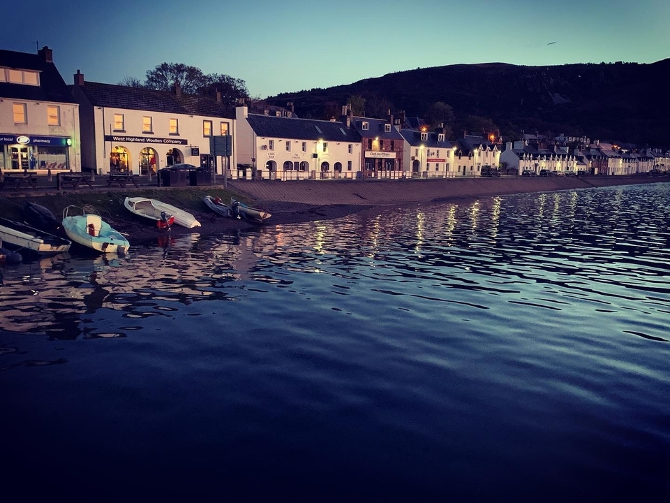 Village côtier au crépuscule avec des bateaux le long du rivage.