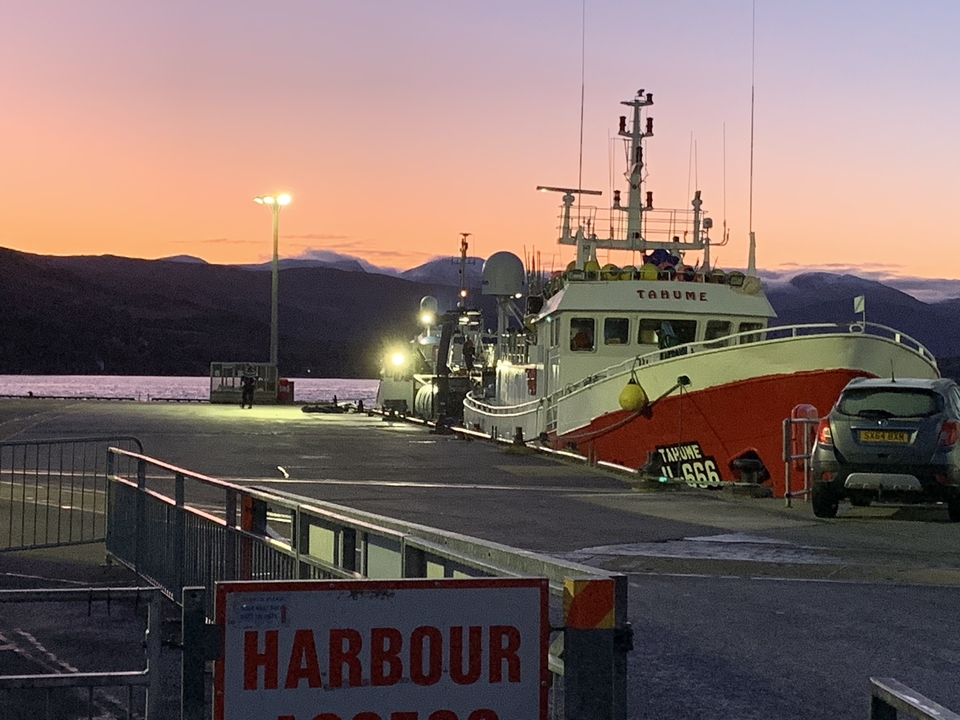 Bateau de pêche amarré dans un port au coucher du soleil.