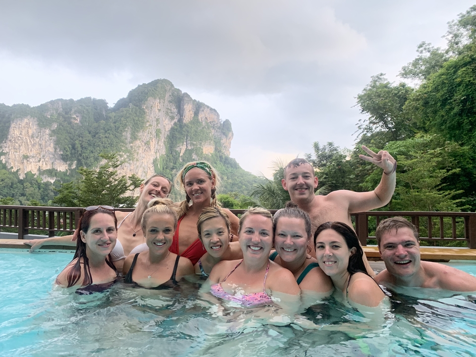 Group of people having fun in a pool with mountains.