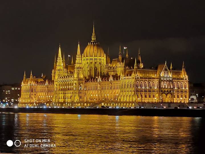 Un bâtiment historique magnifiquement éclairé la nuit le long d'une rivière.