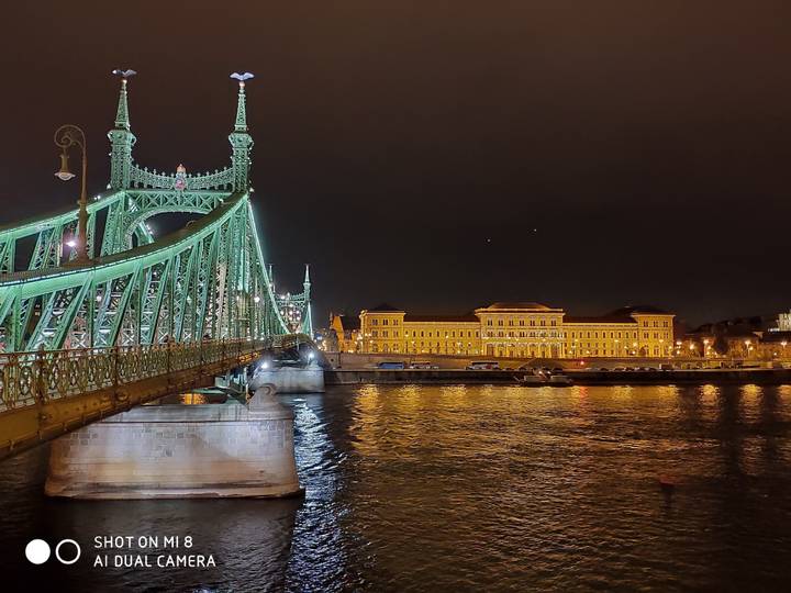 Pont et bâtiment illuminés la nuit au-dessus d'une rivière.