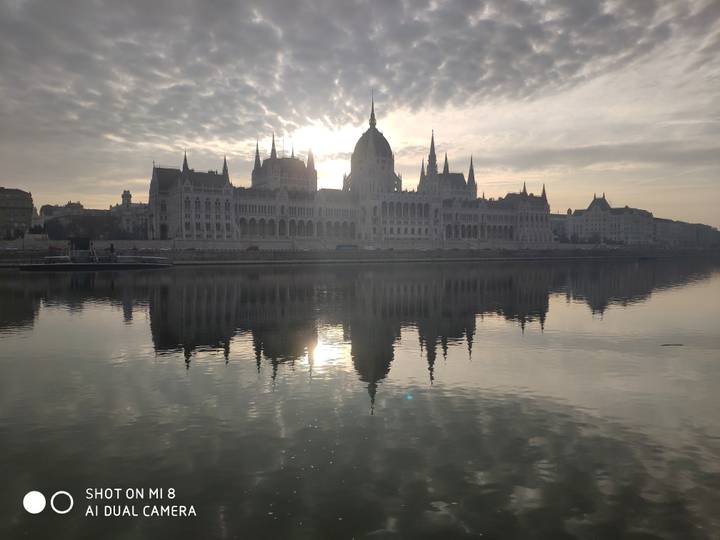 Vue époustouflante d'un bâtiment grandiose avec un reflet dans une rivière au coucher du soleil.
