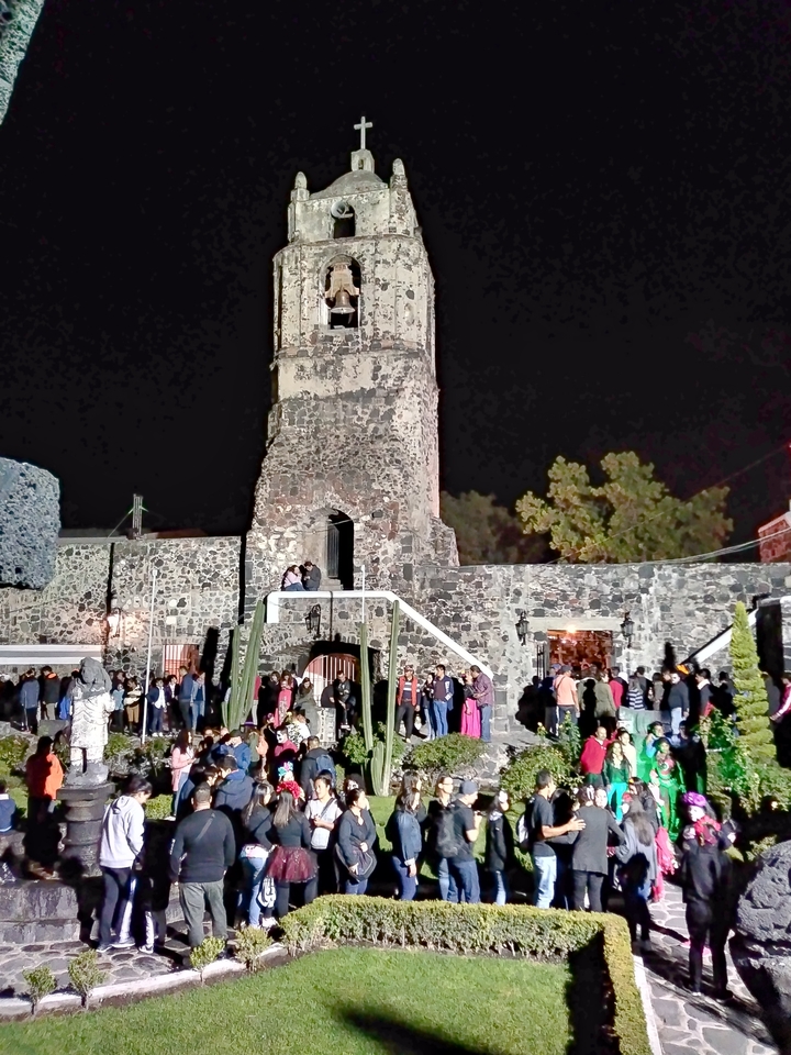 A stone church at night, surrounded by people.
