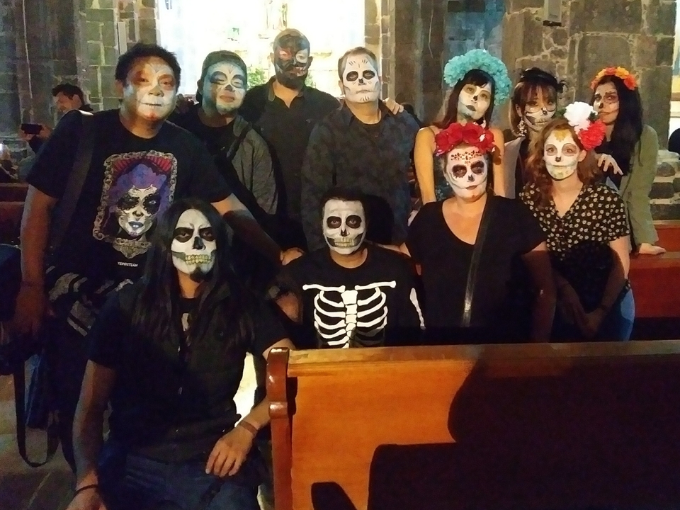 A group of people with faces painted like skulls in a dimly lit room.