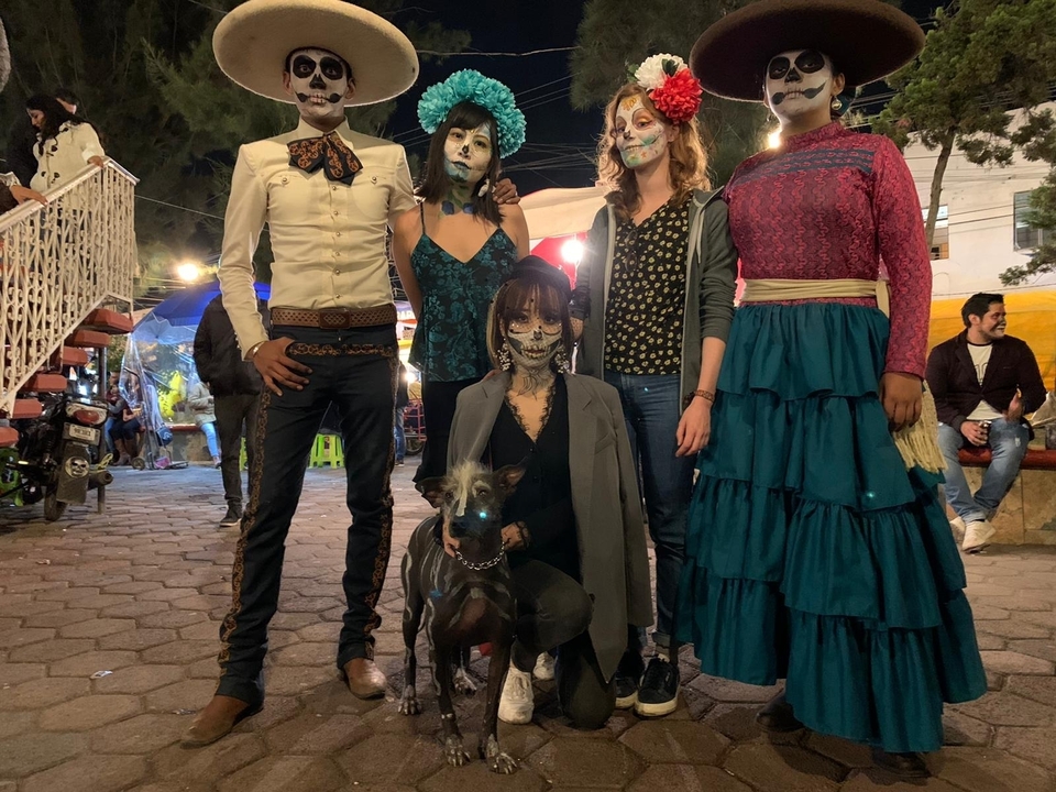 A group of people in costume makeup, standing together, some with a dog.