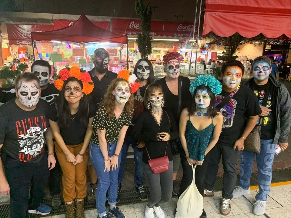 Group of people with face paint and flowers celebrating Day of the Dead.