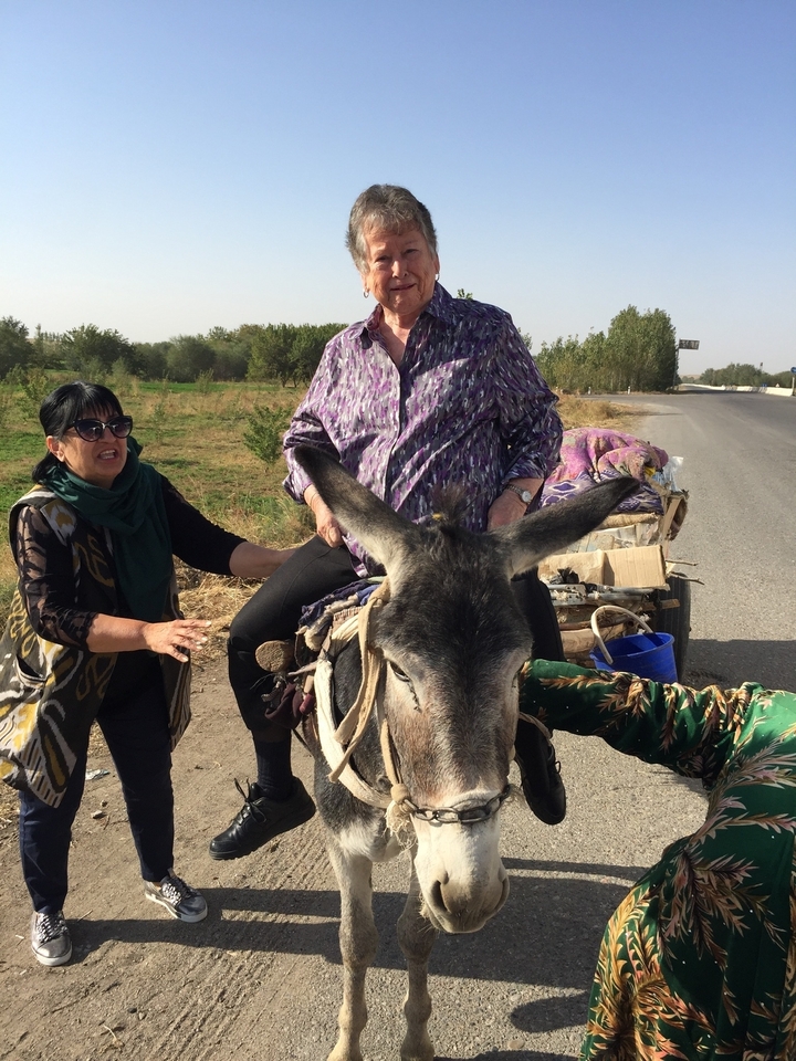 Deux personnes avec un âne sur une route rurale.