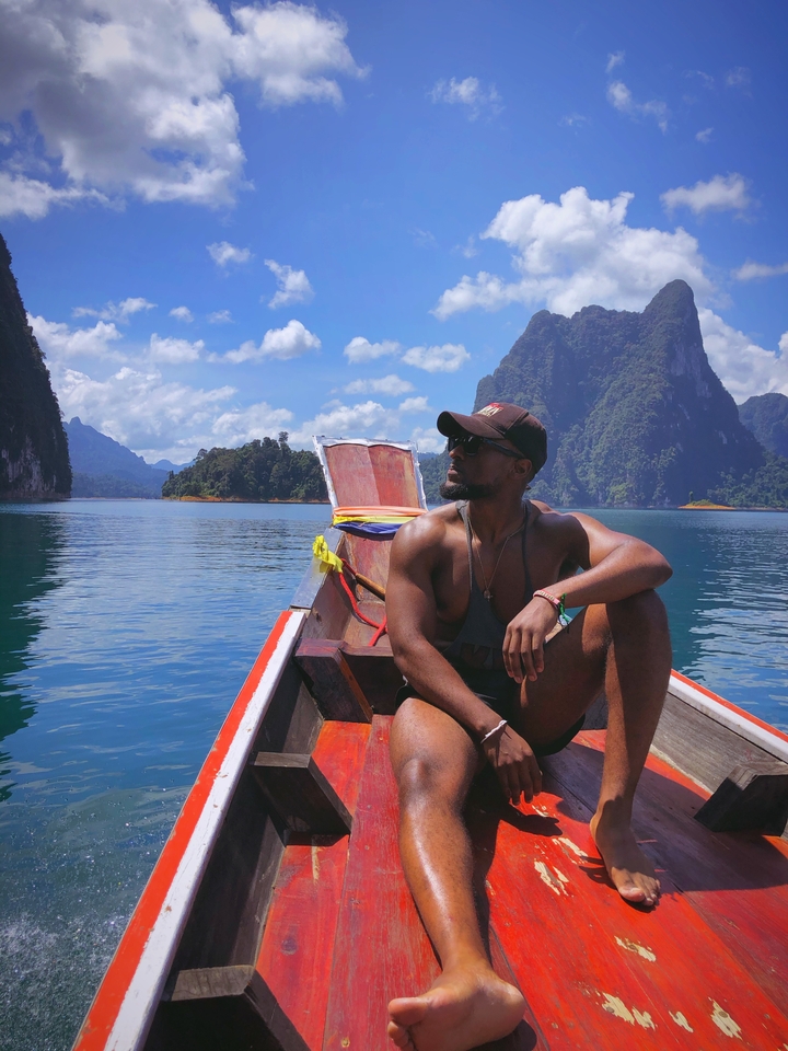 Person sitting on a boat with mountains in the background.