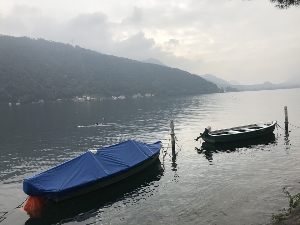 Bateaux amarrés sur un lac calme avec des montagnes en arrière-plan.