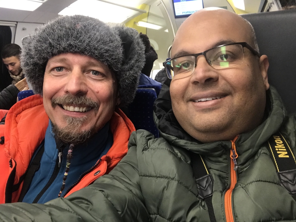 Deux hommes dans les transports en commun, souriant à la caméra.