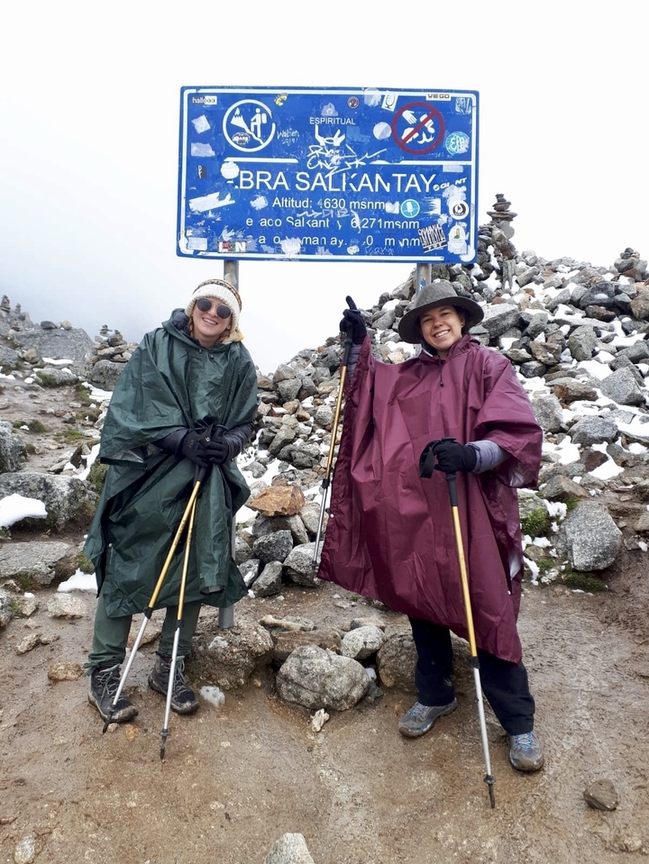 Hikers in ponchos standing on a rocky path.