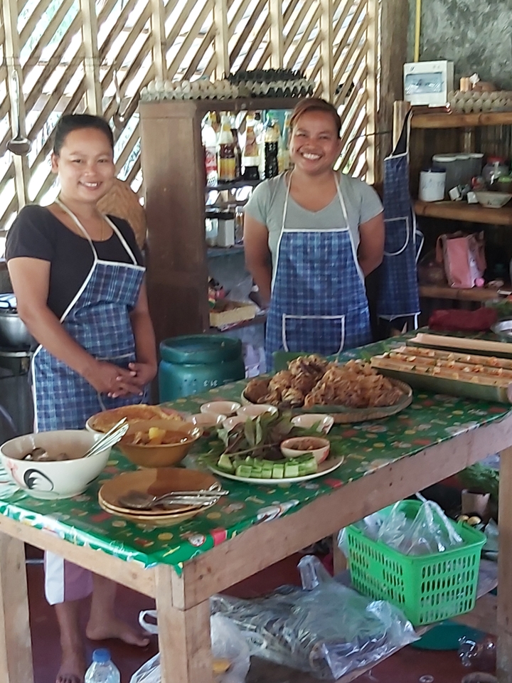 People standing behind a table filled with traditional dishes.