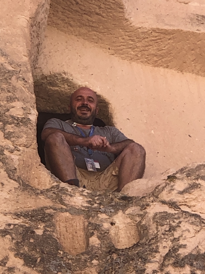 Un homme assis dans un recoin rocheux, souriant.