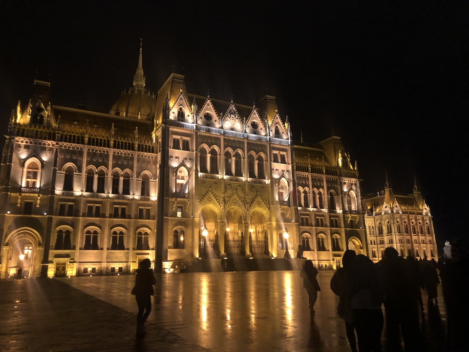 A large illuminated building at night with people in the foreground.