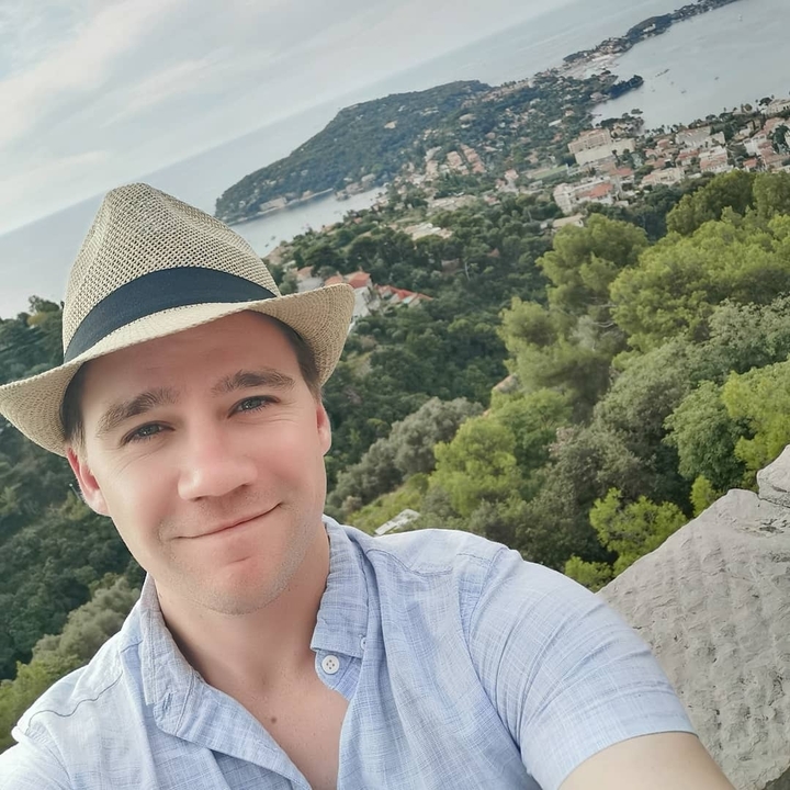 Selfie of a person with a scenic view of a hillside town.