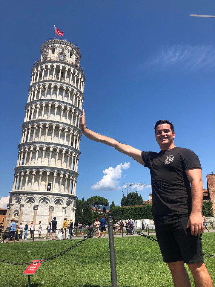 Man doing the illusion pose with the Leaning Tower of Pisa.