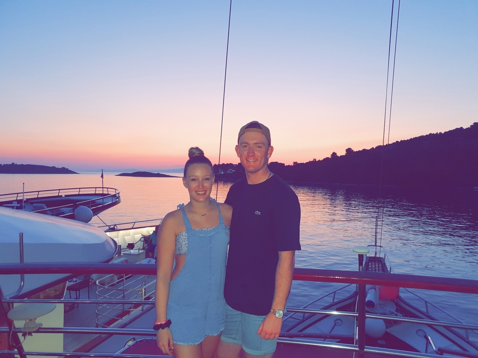 Couple posant pour une photo sur un bateau au coucher du soleil.