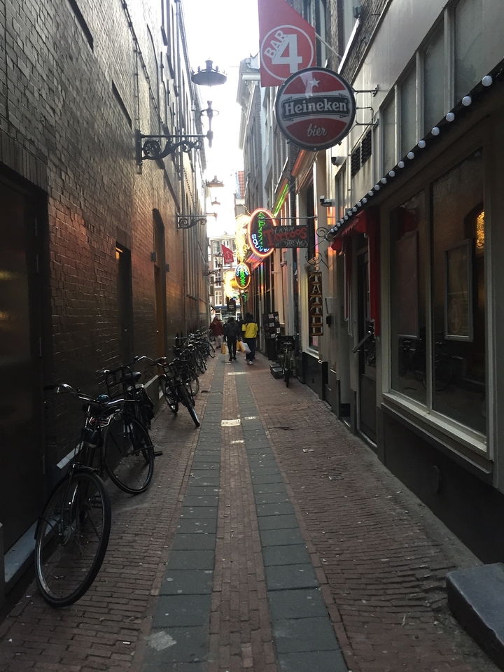 Narrow street with neon signs and bicycles.