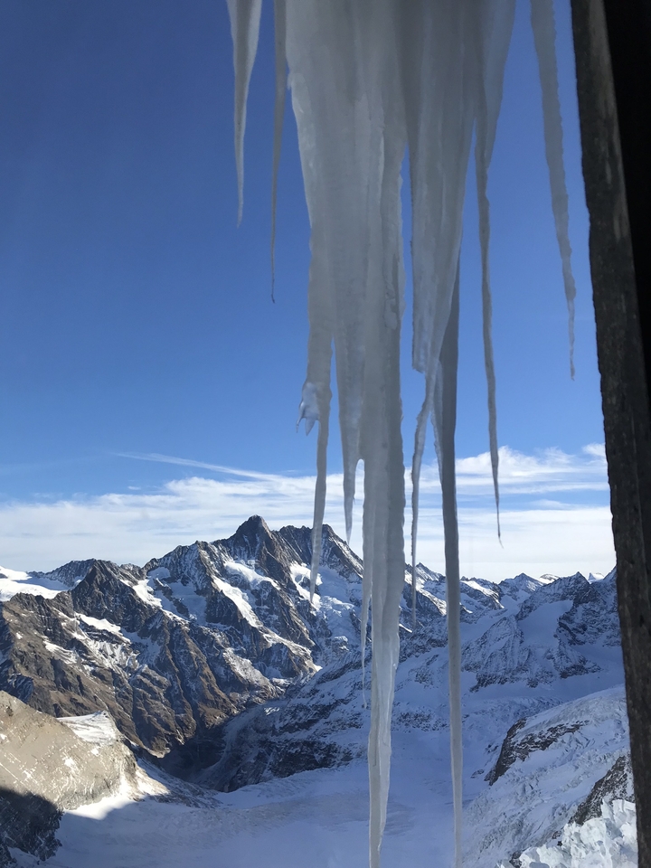 Icicles in the foreground with a snowy mountain range in the background.