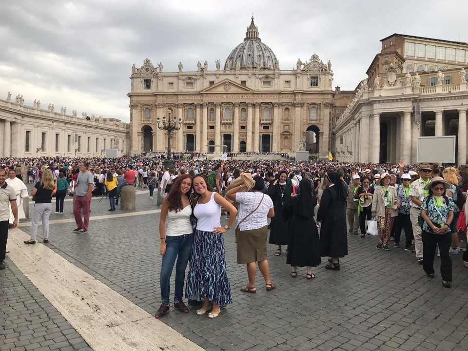Two women posing in a crowded plaza in Vatican City.