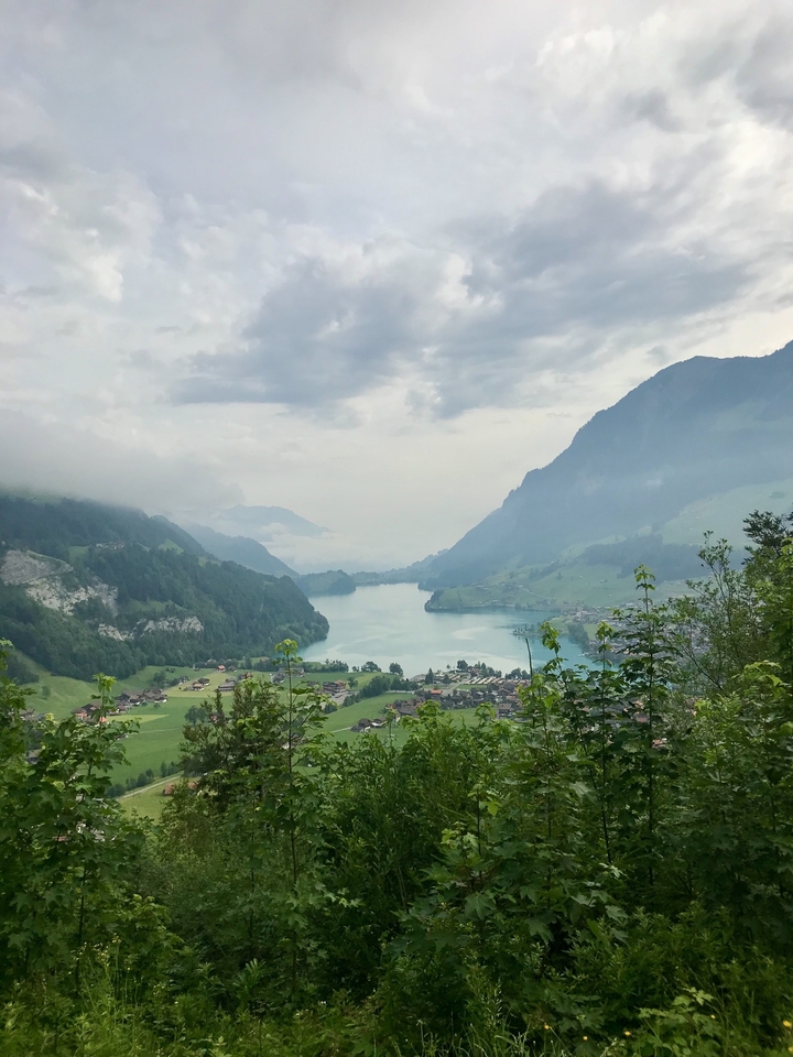 Stunning view of a lake surrounded by mountains and cloud cover.