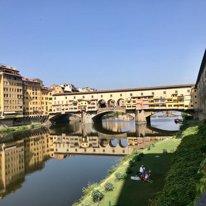 Ponte Vecchio bridge reflected in the river in Florence.