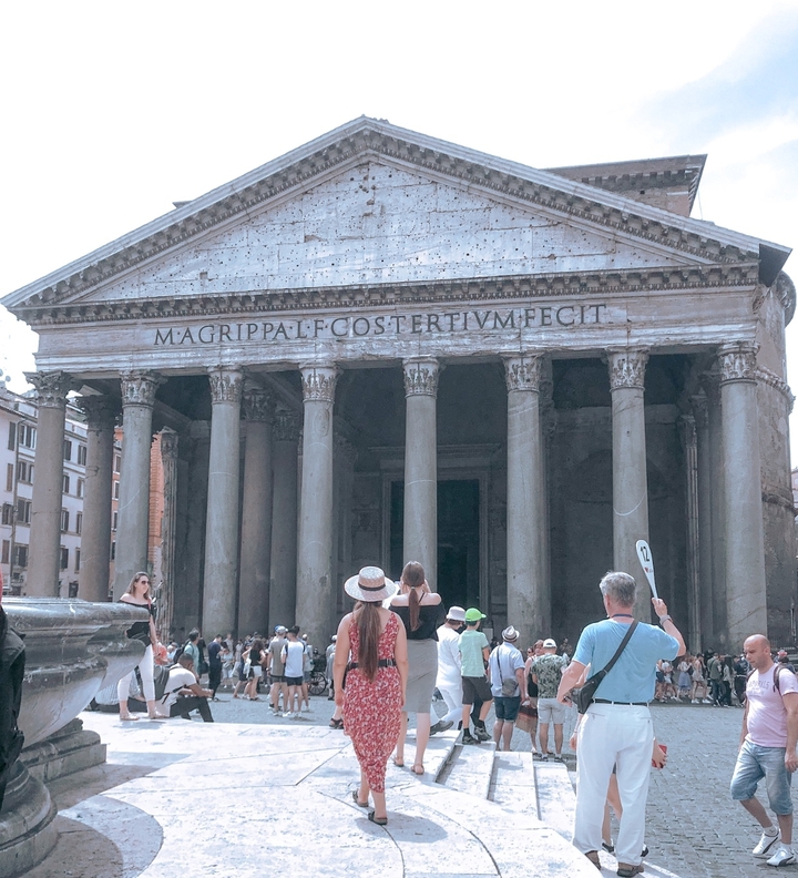 Classical building with tall columns and tourists gathered outside.