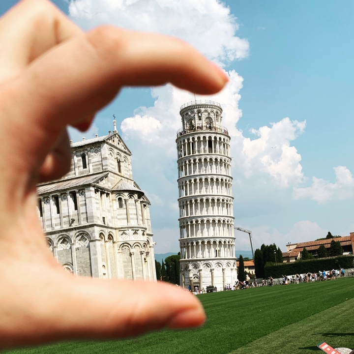 Leaning Tower of Pisa with a hand gesture in the foreground.
