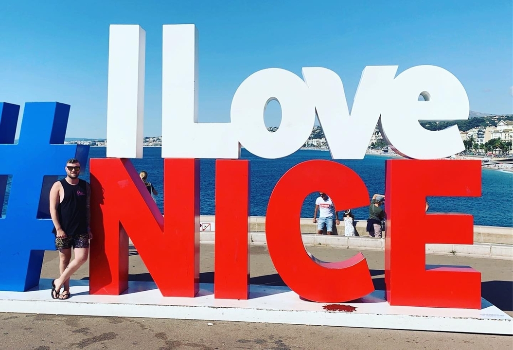 Person standing next to large letters reading 'I LOVE NICE'.