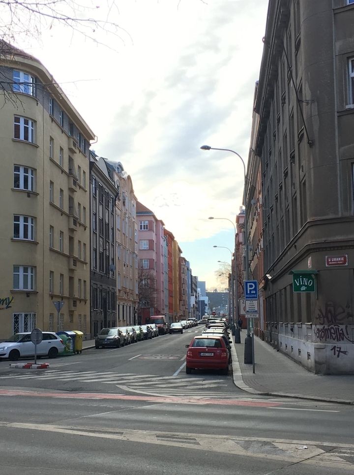Colorful street with parked cars and classic architecture.