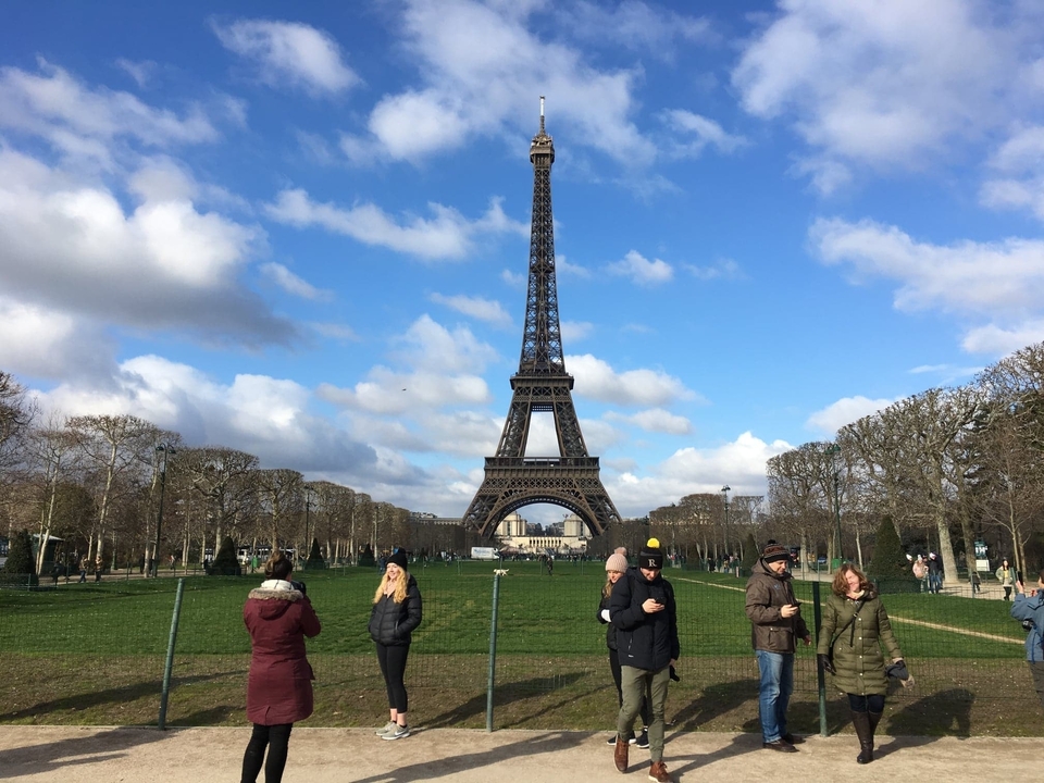 Iconic Eiffel Tower in an open park area with people around.