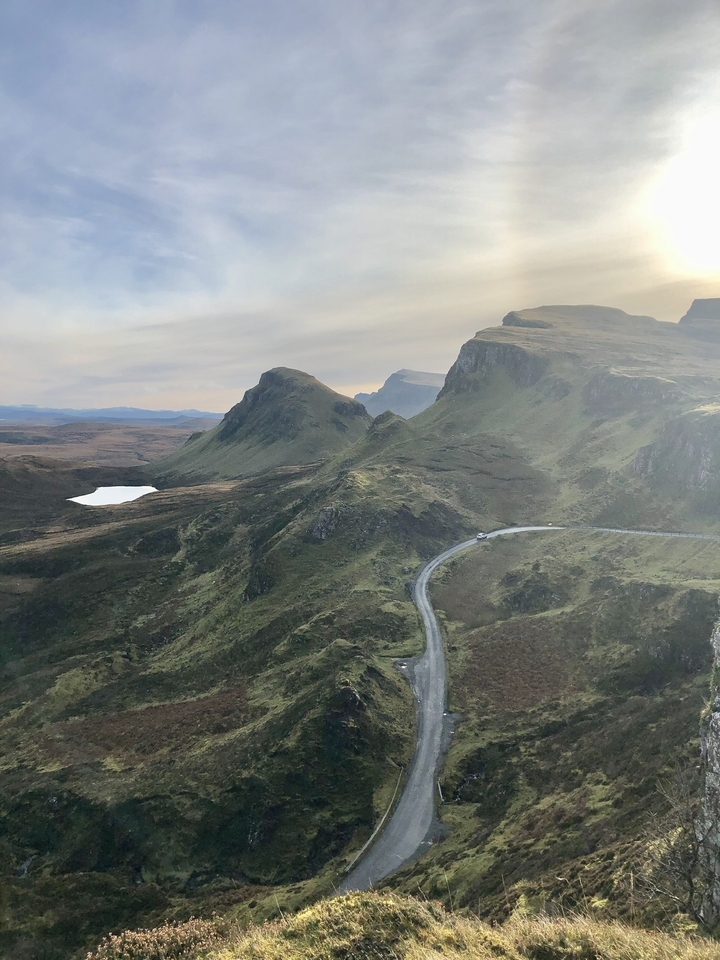 Majestic landscape featuring a curving road through rugged hills.