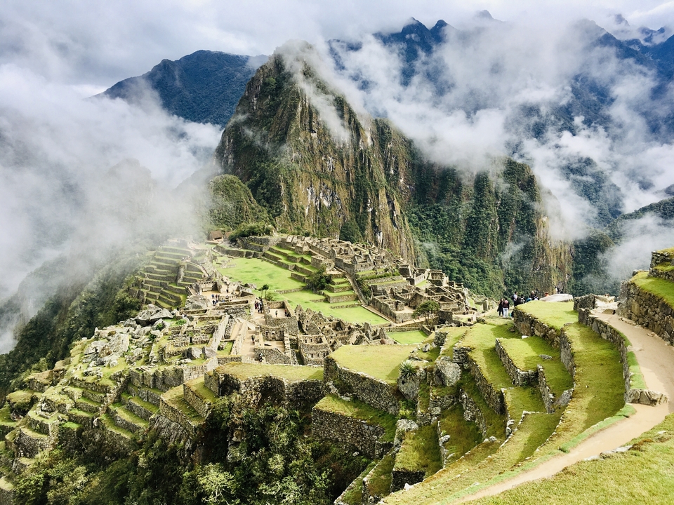 Vue aérienne du Machu Picchu avec des nuages entourant les montagnes.