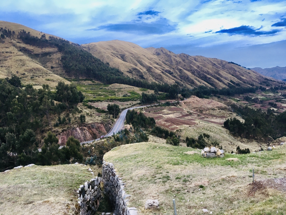 Collines ondulantes et terres agricoles avec un ciel bleu et des nuages.