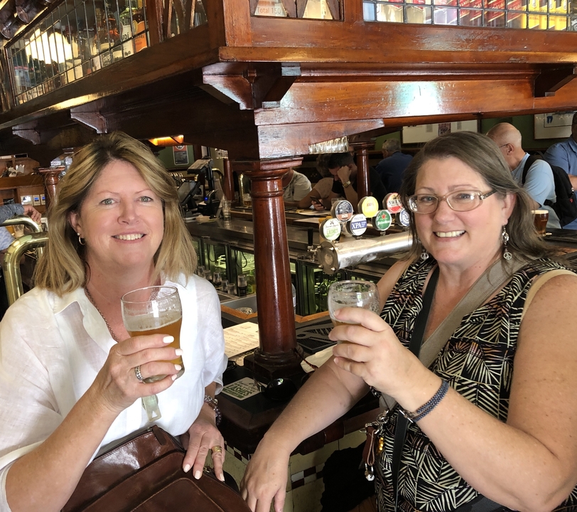 Deux femmes savourant des boissons dans un bar avec des tireuses à bière visibles.