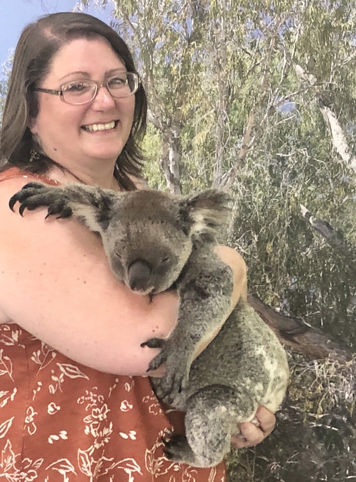 Personne tenant un koala avec un arrière-plan naturel.