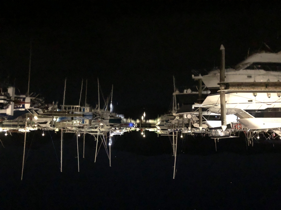 Vue nocturne d'un port de plaisance avec des bateaux amarrés.
