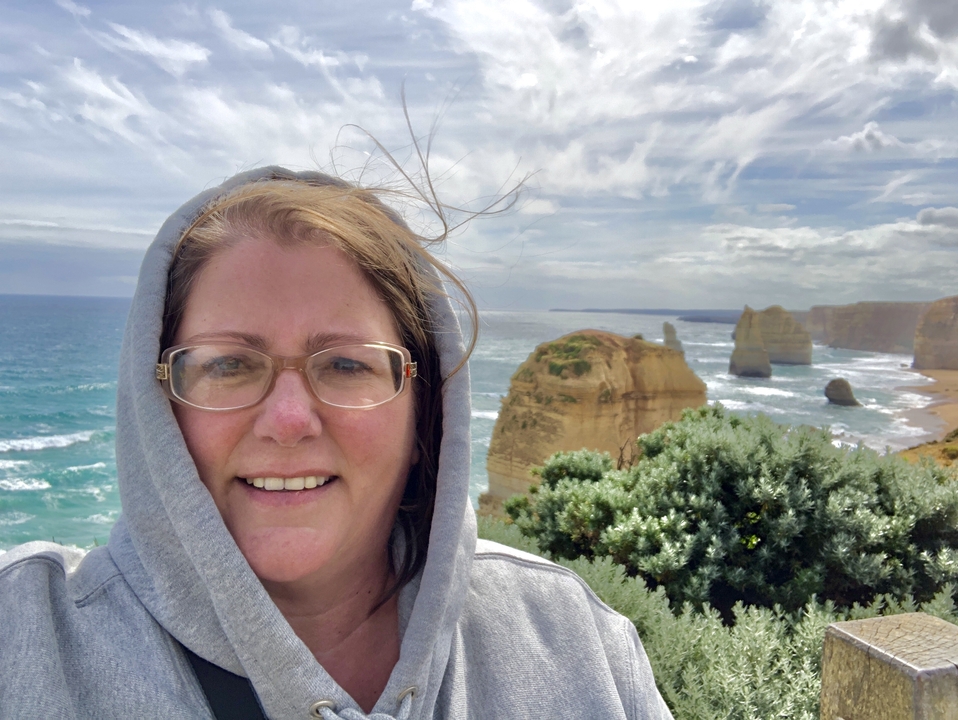 Femme posant avec les formations rocheuses des Douze Apôtres en arrière-plan.