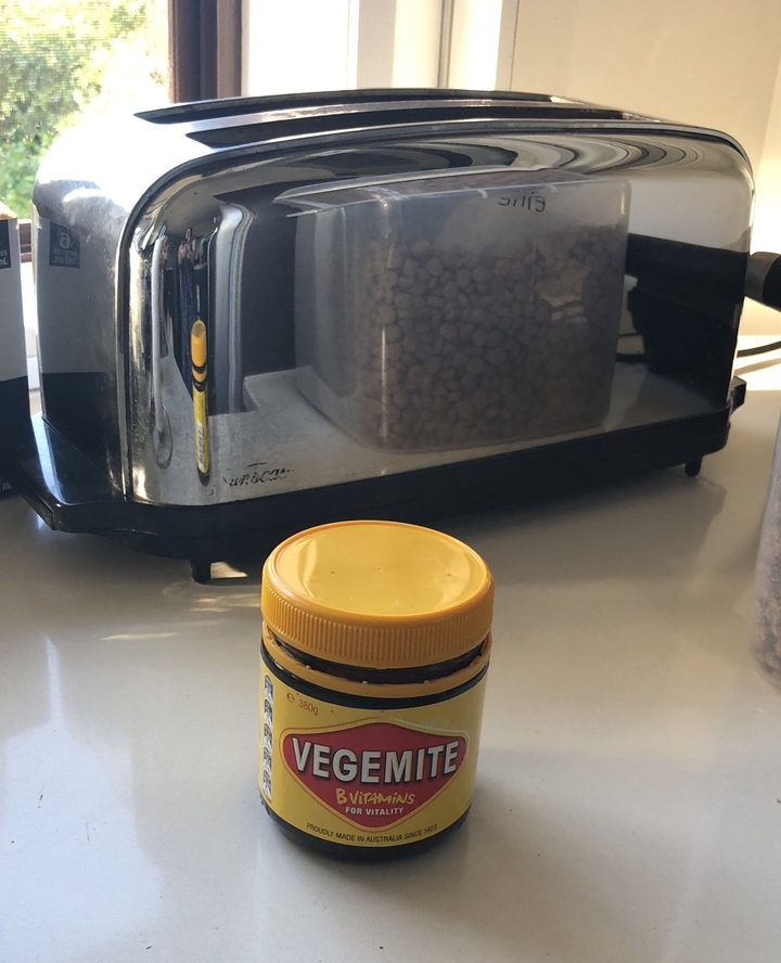 Récipient avec couvercle jaune sur une table devant un appareil de cuisine.