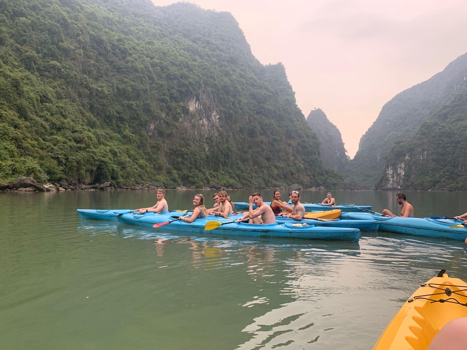 Group of people kayaking in calm waters surrounded by limestone cliffs.