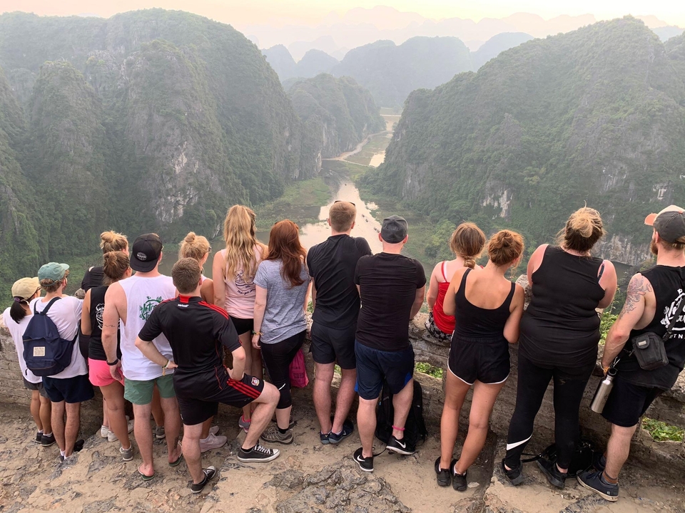 A group of people overlooking a scenic river valley from a high viewpoint.