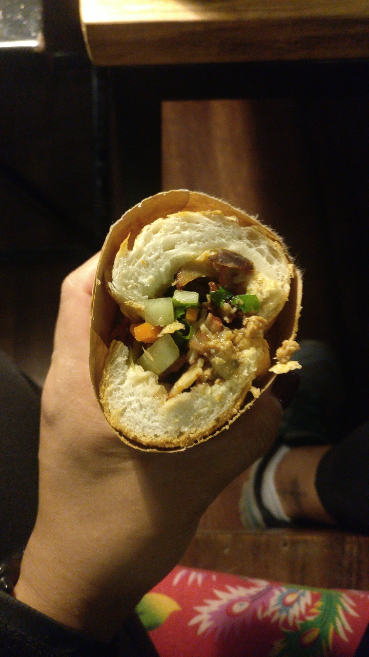 Un gros plan d'un sandwich avec des légumes et de la viande à l'intérieur.