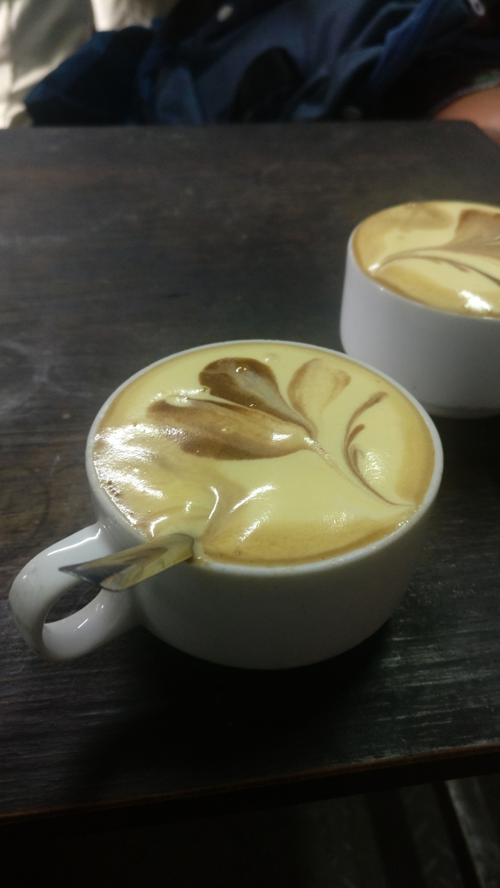 Une tasse de café avec de l'art latte sur une table en bois.