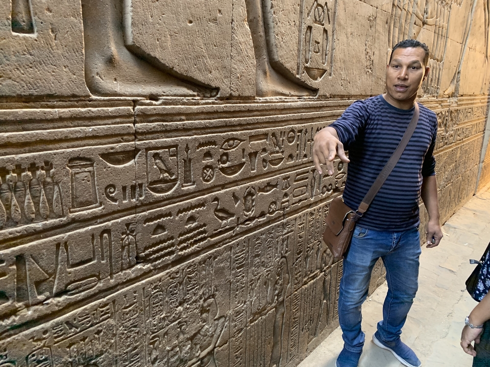 Guide touristique illustrant les sculptures égyptiennes le long d'un mur