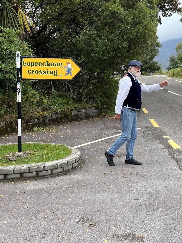 Man pointing at a leprechaun crossing sign.